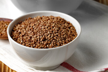 Bowl of raw uncooked buckwheat on wooden table
