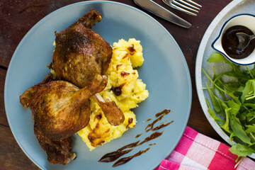 Festive roast duck on wooden table with oranges, hoi sin sauce and arugula leaves.