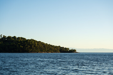 The green coast and blue sea of the Greek island Skopelos of the Sporades in sunset
