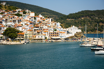 Fototapeta na wymiar The historical town on Skopelos island seen from the boat when entering the harbor in summer light.