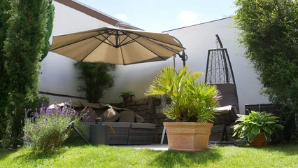 Foto op Plexiglas Gartenterrasse mit Loungegruppe, Sonnenschirm und Hängesessel in einer Gartenecke mit Säulen-Faulbaum und umgeben von einer Palme und Zypressen  © turtles2