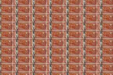 50 Canadian dollars bills printed in money production conveyor. Collage of many bills. Concept of...