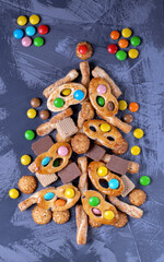 Obraz na płótnie Canvas Christmas tree made of different cookies, waffles and candies. Top view. Creative festive background