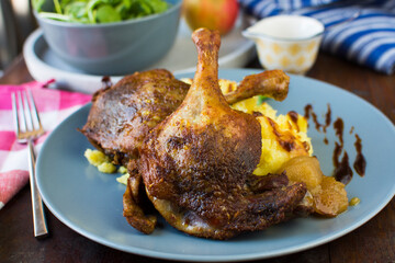 Festive roast duck on wooden table with oranges, hoi sin sauce and arugula leaves.