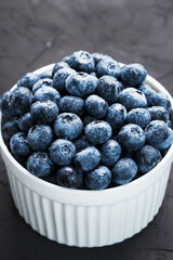 Organic blueberries in a white Cup on a black Board.