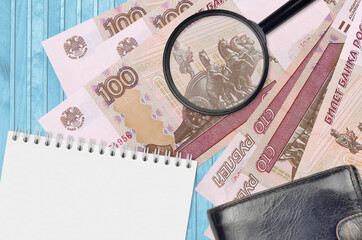 100 russian rubles bills and magnifying glass with black purse and notepad. Concept of counterfeit...