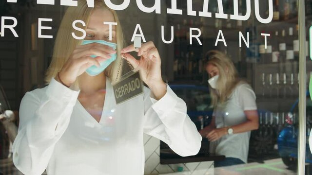 cafe or restaurants and business reopen after coronavirus quarantine is over. woman with face mask turning a sign on a door shop. small business after covid lockdown. Spain, barcelona