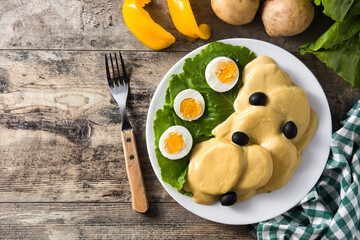 Traditional Peruvian papa a la huancaina on wooden table. Top view. Copy space	