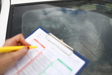An agent draws up documents for broken windshield in car. Services of insurance companies concept