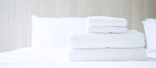 Fototapeta na wymiar Stack of white towel and Bathrobe on bed in luxury hotel or resort. Laundry, Relax, holiday, spa, massage and vacation concepts