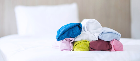 Stack of colorful T shirt on bed in luxury hotel or resort or home. Relax, summer clothes, laundry and vacation concepts
