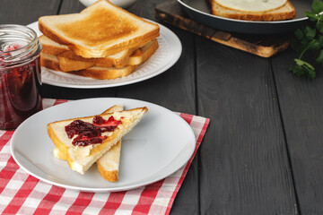 Toasted bread slices with berry jam on wooden table