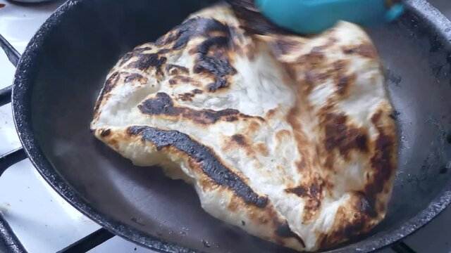 Flipping charred tasty Indian Partha hot pancake cooking on stove in pan