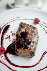 Venison meat with raspberry sauce on a white plate. On a white wooden table.
