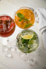 Assorted cold cocktails - mojito, orange and raspberry. On a wooden, white table
