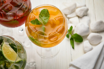 Assorted cold cocktails - mojito, orange and raspberry. On a wooden, white table
