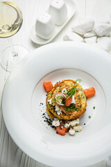 Pancakes with salmon, cheese, herbs. On a white wooden table
