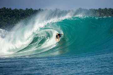 Surfer on perfect blue big tube wave, empty line up, perfect for surfing, clean water, Indian Ocean in Mentawai islands