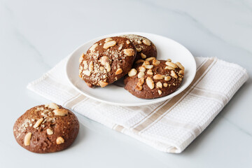 chocolate chip cookies with nuts and peanuts in a white tea plate on a table with a tea napkin