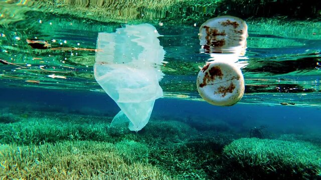 Improper Disposal Of Garbage Resulting To Pollution - Plastic Bag And Bottle Floating On The Blue Sea.  - close up shot