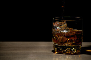 Glasses of whiskey with ice on wood