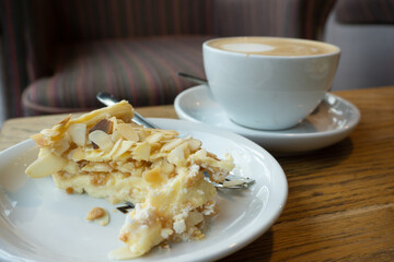 A cup of coffee and cake with cream and almond