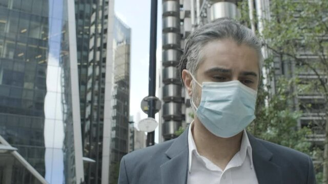 Corporate business man commuting to work wearing face mask in the city of London during Covid-19 Pandemic