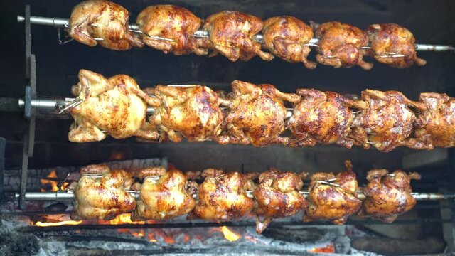 Rotisserie Chicken Roasted chickens on spit grilled over wood fire of a big barbecue.