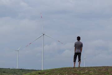 Indian man standing in front of the windmills at Wankaner, Gujarat, India