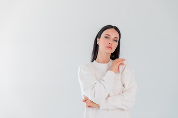 Hipster young girl over wall. Beautiful adult girl model in white sweater hoody isolated over gray...
