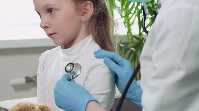 The doctor listens to phonendoscope breath of a blonde girl. The girl has a cold