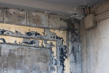Part of the wall of the old theater with peeling paint of different colors: gray, black, brown. A box with electrical wires in the corner of the building. 