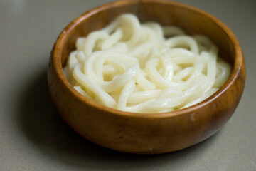 Steaming bowl of Japanese udon noodles in a round wooden bowl.