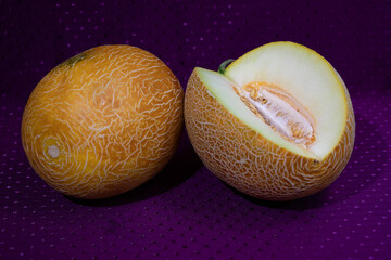Two melons on a purple background. Seeds inside the fruit. Yellow summer.