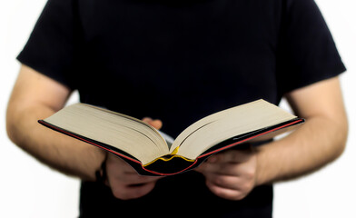 man with black t-shirt reading a thick book, standing up