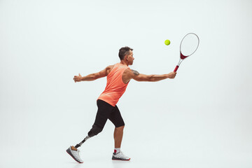 Fototapeta na wymiar Athlete with disabilities or amputee isolated on white studio background. Professional male tennis player with leg prosthesis training in studio. Disabled sport and healthy lifestyle concept.
