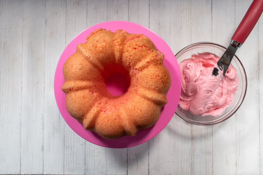 Pink Strawberry Cake On Bright Pink Cake Stand With Bowl Of Pink Frosting