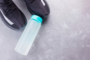 Fitness concept with sneakers and bottle of water. Sports equipment on a gray background. Healthy lifestyle concept. Copy space. Top view