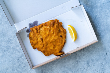Take Away Schnitzel Cordon Bleu with lemon in Plastic Box Container / Package.