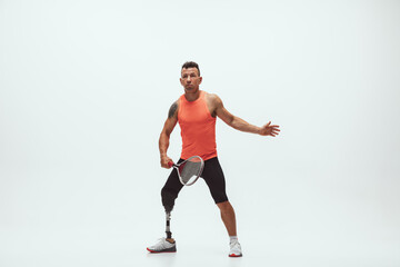 Fototapeta premium Athlete with disabilities or amputee isolated on white studio background. Professional male tennis player with leg prosthesis training in studio. Disabled sport and healthy lifestyle concept.