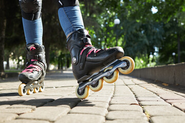 leisure activity at public park. close up view roller skate. girl wearing knee protection over jeans. sports lifestyle concept. copy space.