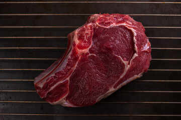 Raw Fresh Meat For The Steak Ribeye is on the Grill. View From Above. Black Cast Iron Background