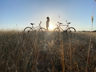 silhouette of young woman on bike in the field
