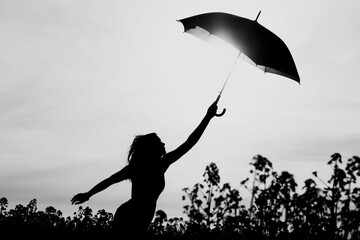 Unplugged free silhouette woman umbrella up to black white sky. Nature girl at windy rainy day has adventure wanderlust. Wonderful scene of imagination power and departure to new horizons in youth