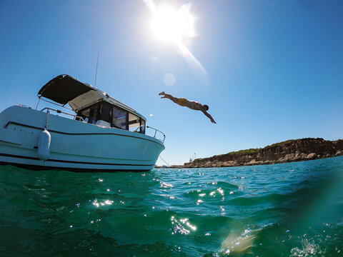 young woman jumping from a boat in summer