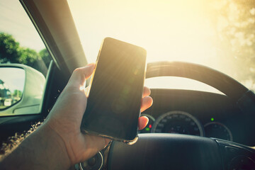 Driver hand using smartphone on steering wheel of a car