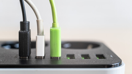 Modern convenient multi-port usb charger for devices. Close-up of multi-colored cables in a power...
