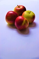 Four ripe red and green Braeburn apples on light background with copy space