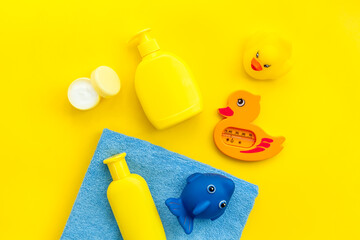 Bath accessories for kids. Yellow rubber duck,towel, cream, shampoo on Yellow  background top view