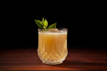 Scotch, mint, absinthe, lemon juice cocktail on a black background